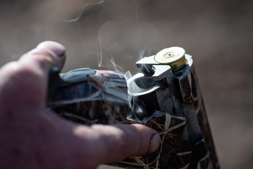 Smoke comes out of from the chamber from a shot gun that was fired, opened, and a spent cartridge just removed.