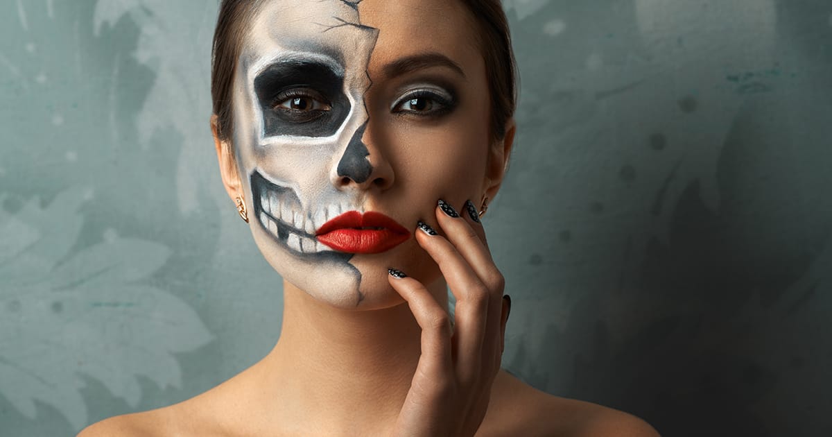 Image shows woman wearing skull makeup.