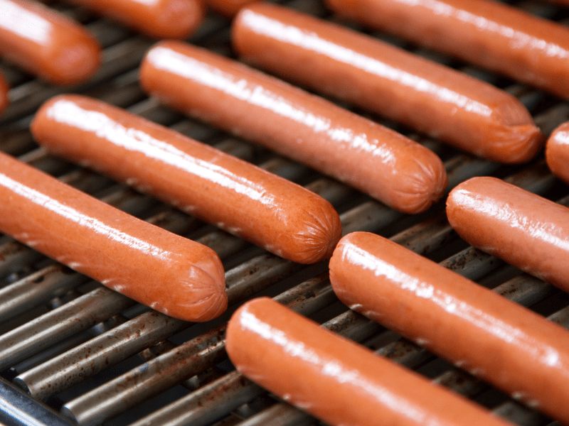 Image shows hot dogs cooking.