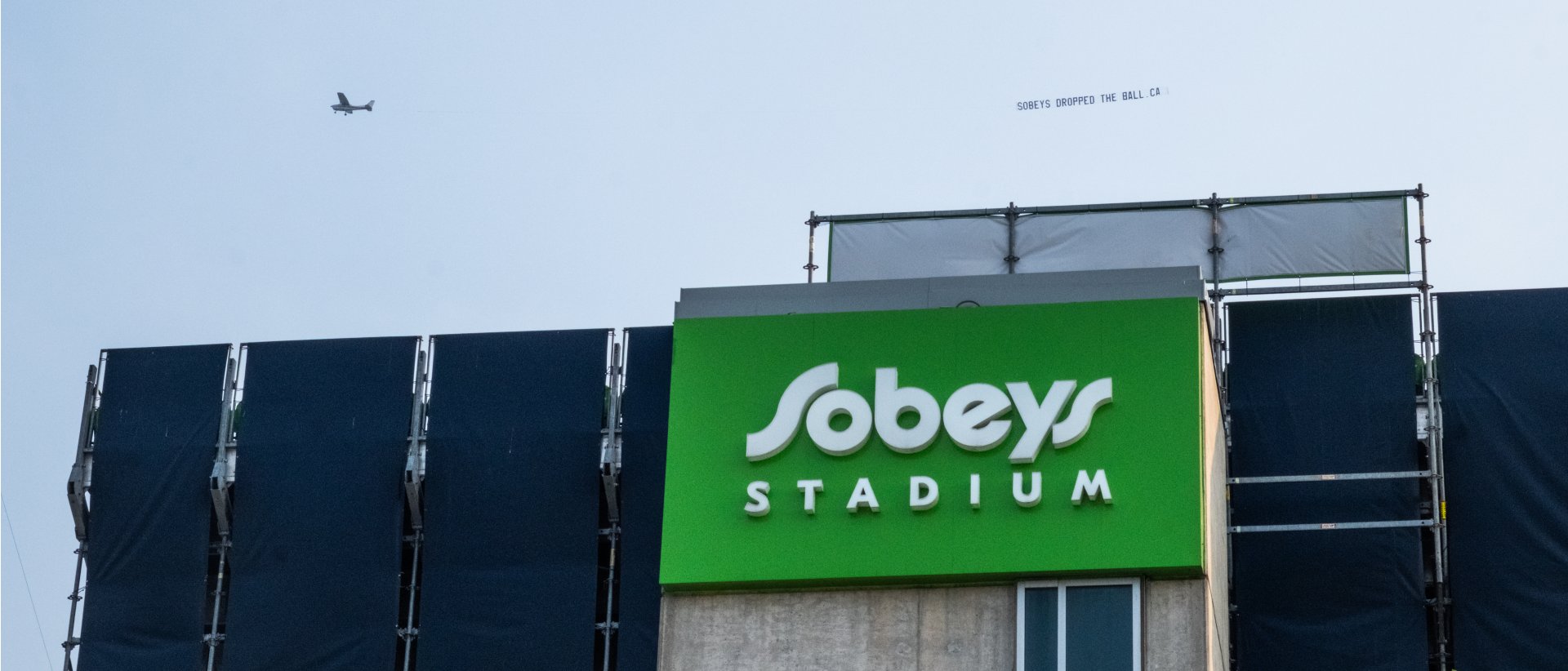 Plane flying over Sobey's Stadium with sign: SobeysDroppedTheBall.ca