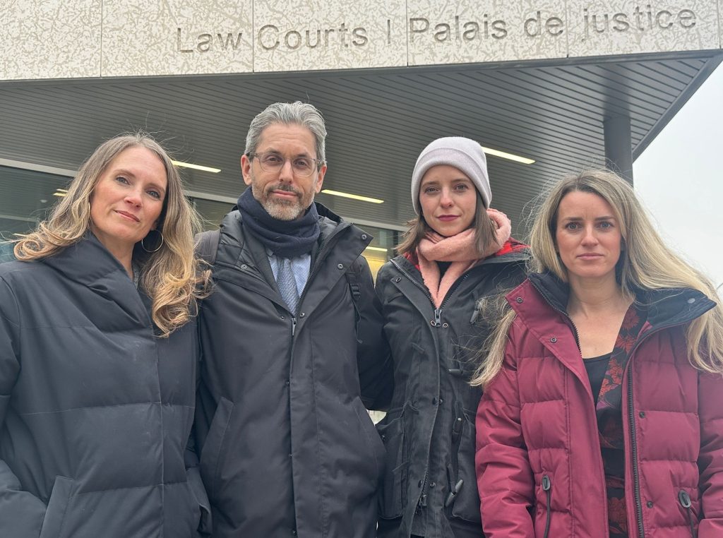 According to Gemini Four Animal Justice lawyers are standing in front of a court building. Above them, a sign on the building reads "Courts of Law | Palace of justice" in engraved letters.